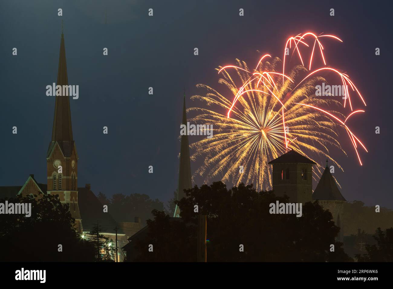 Fireworks explode over church steeples durng an Independence Day