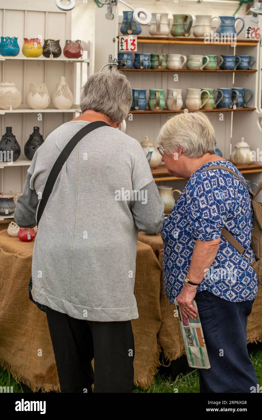two older lady friends browsing a pottery stall at a country fair on the isle of wight Stock Photo