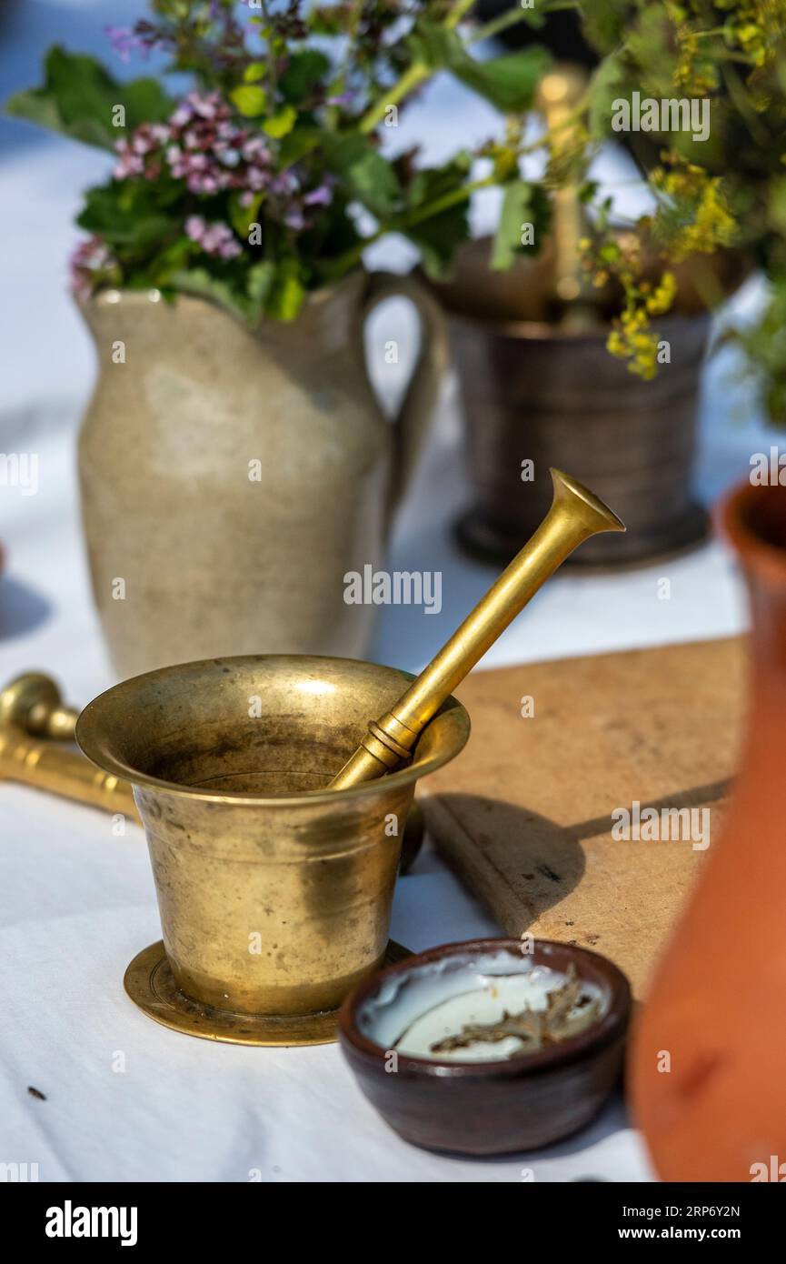 traditional brass mortar and pestle with jugs, jars and pots being used by an apothecary to mix herbs and spices into tinctures and concoctions. Stock Photo