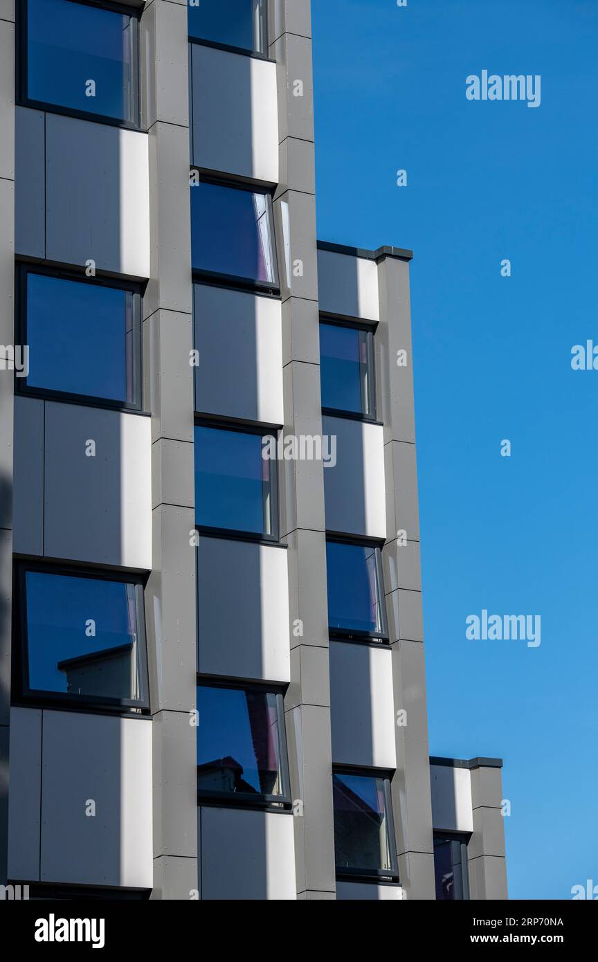 abstract modern building block of flats with different floors or levels and a blue sky background. Stock Photo