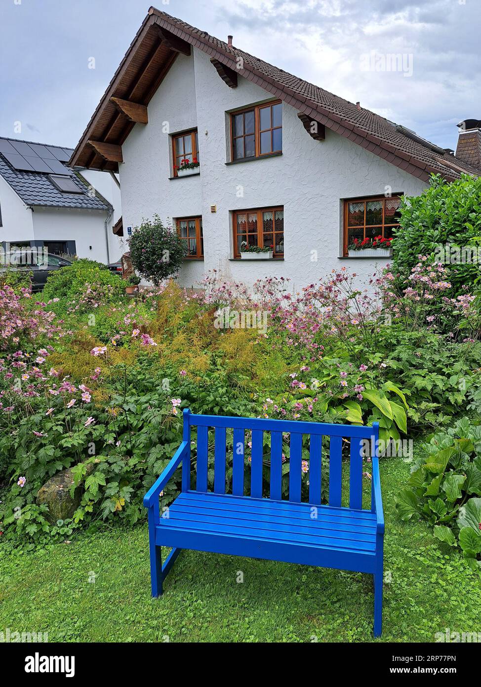 blaue Bank vor einem Einfamilienhaus im Landhaus-Stil Stock Photo