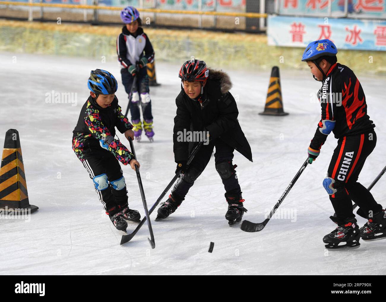 (190201) -- BEIJING, Feb. 1, 2019 (Xinhua) -- Photo taken on Jan. 9, 2019 shows students playing ice hockey during a skating training session at Taipingzhuang Central Primary School, in Yanqing District of Beijing, capital of China. Taipingzhuang Central Primary School situated right at the foot of Xiaohaituo Mountains, where the venues for Beijing 2022 Winter Olympic games are under construction. Teachers of Taipingzhuang Central Primary School have turned an experimental farmland into a seasonal skating rink for the pupils here to learn skating since 2016. The school hired a experienced coac Stock Photo