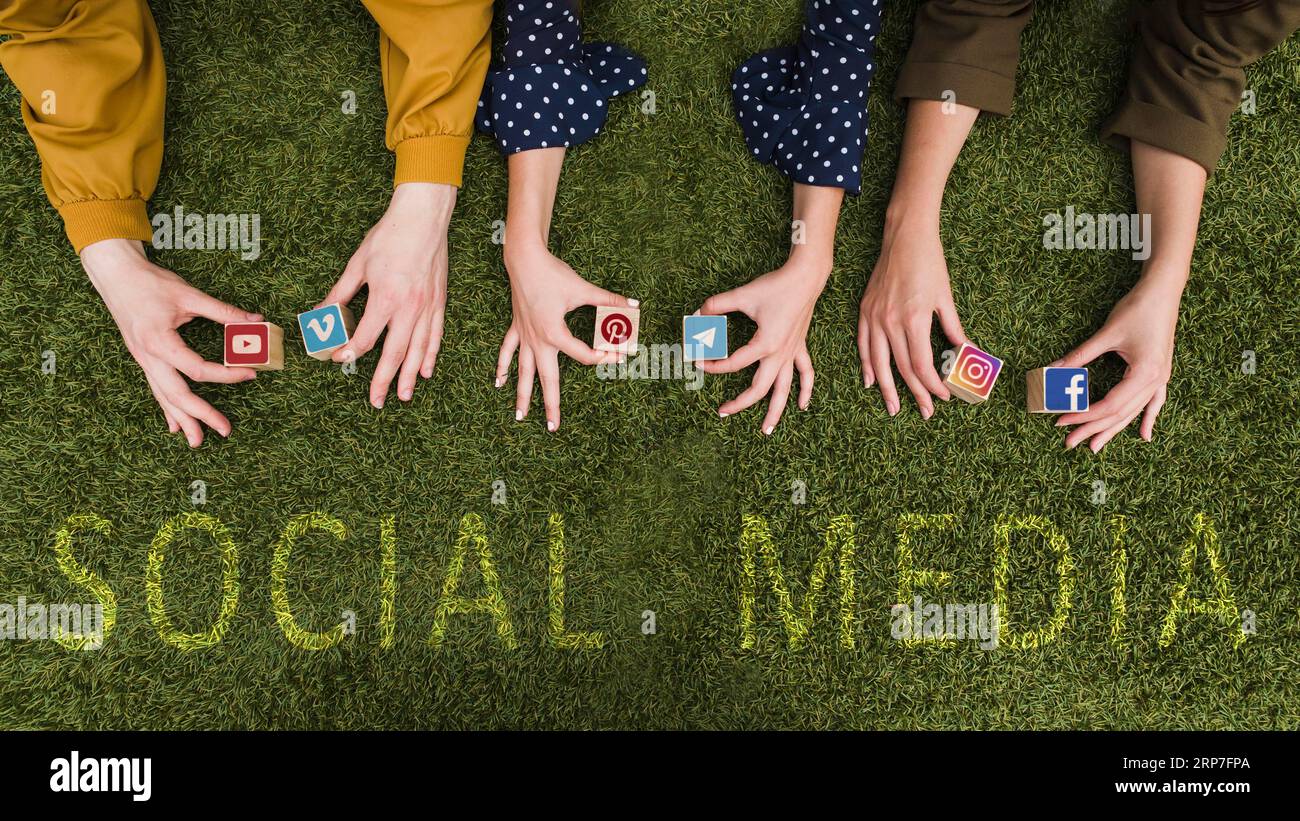 Overhead view female s hand holding social network app symbol blocks lawn Stock Photo