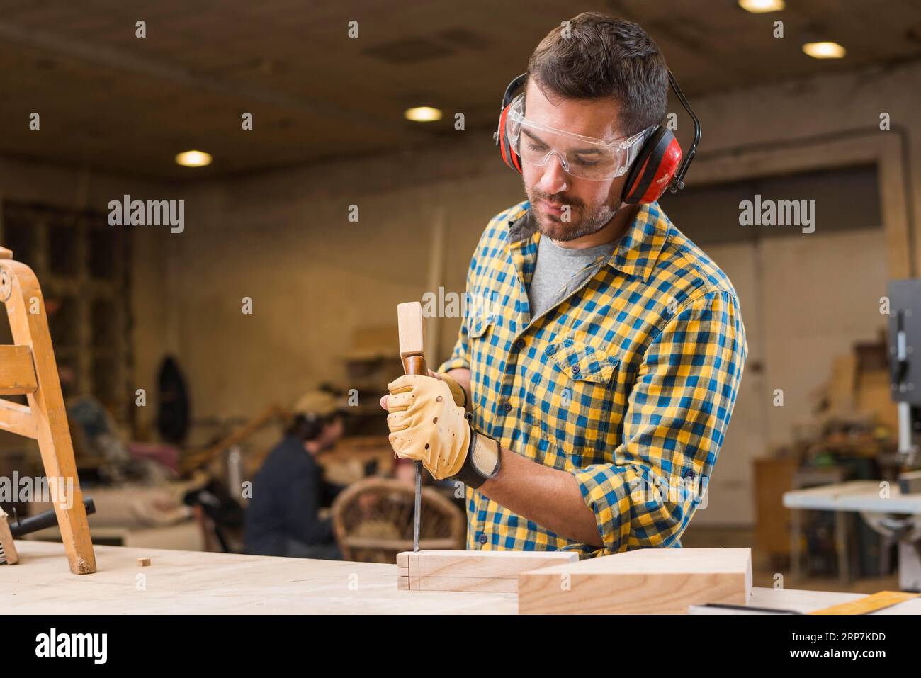 Close up carpenter hitting hammer chisel wooden block workshop Stock Photo