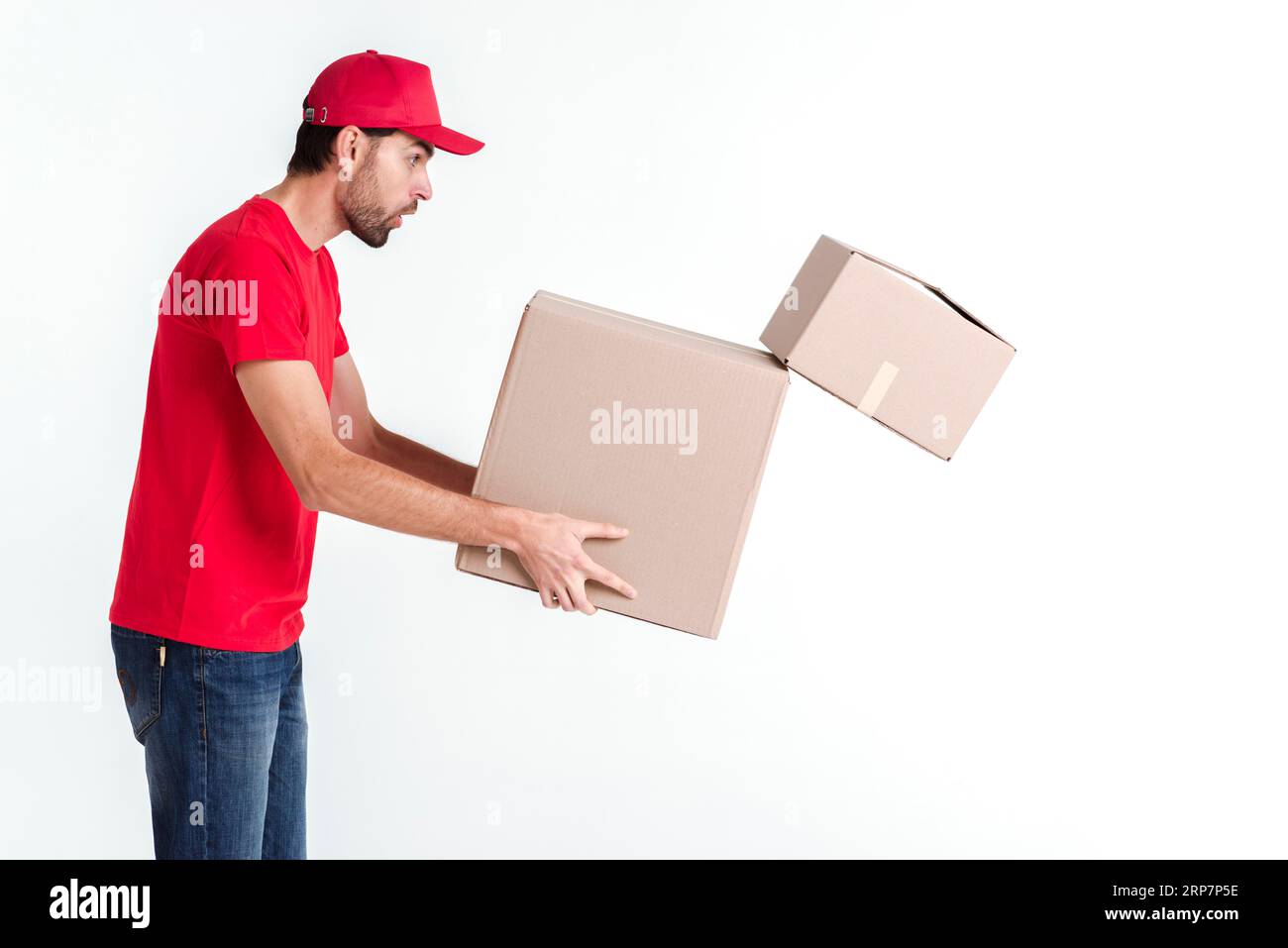 Side view delivery boy holding parcel post boxes drops one Stock Photo