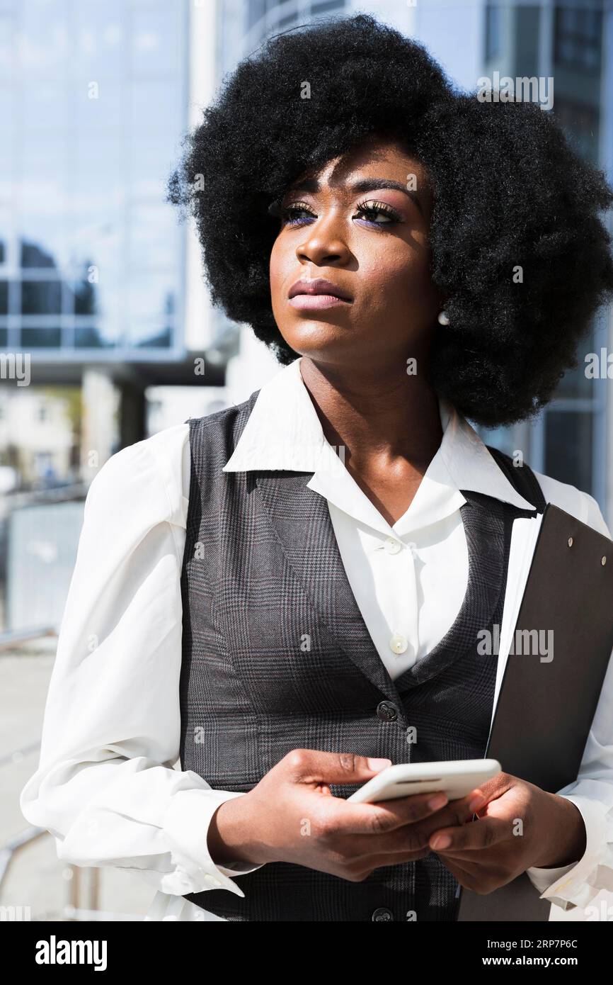 Portrait african young businesswoman holding mobile phone hand looking away Stock Photo