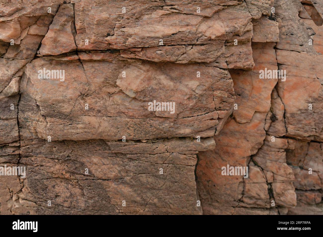 Peach coloured stone background with some cracks and at various levels ...