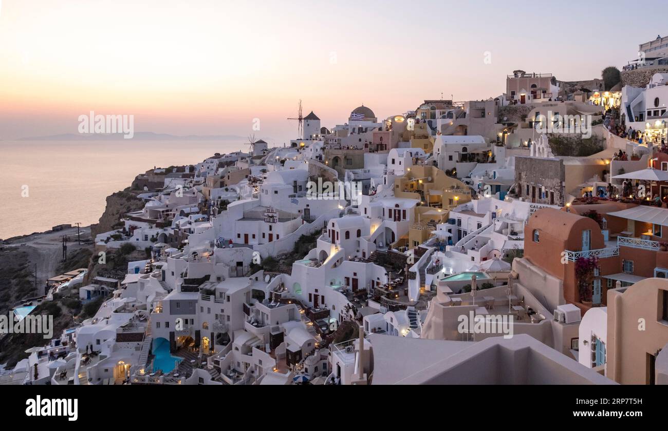 Cliff-side houses, villas and windmill in the village of Oia, Ia, as seen from the Kasteli Castle, Santorini, Greece Stock Photo