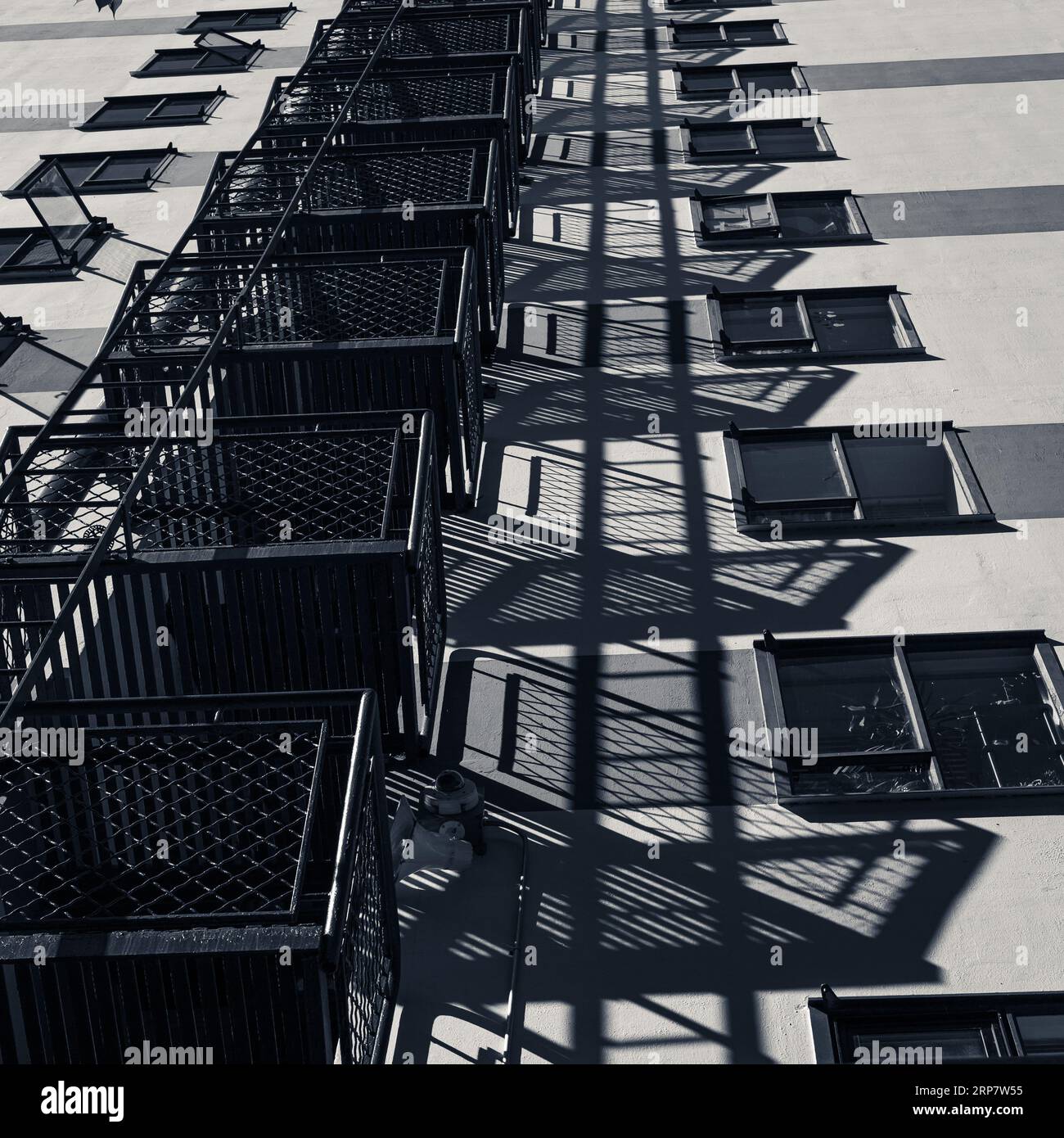 Fire escape and shadows on the side of a building in black and white Stock Photo