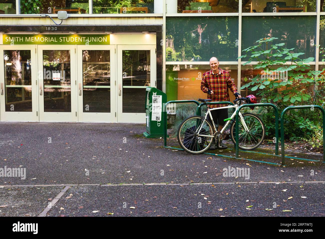 Man locking up his bike outside the Smith Memorial Student Union building at Portland State University in Portland Oregon Stock Photo