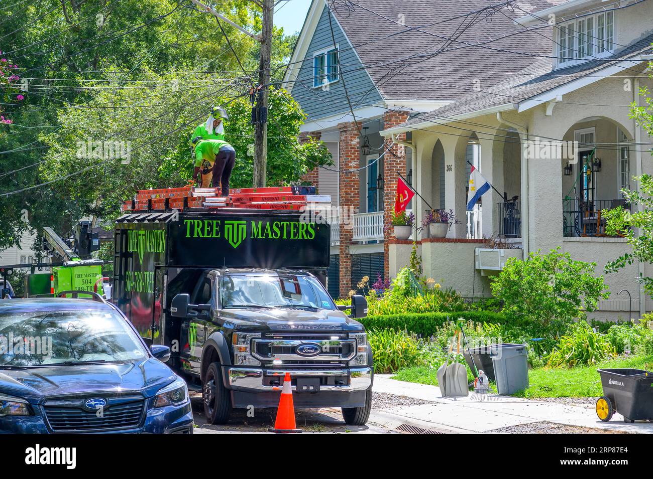 NEW ORLEANS, LA, USA - AUGUST 10, 2023: Workers atop Tree Masters tree service truck stow away equipment in Uptown neighborhood Stock Photo