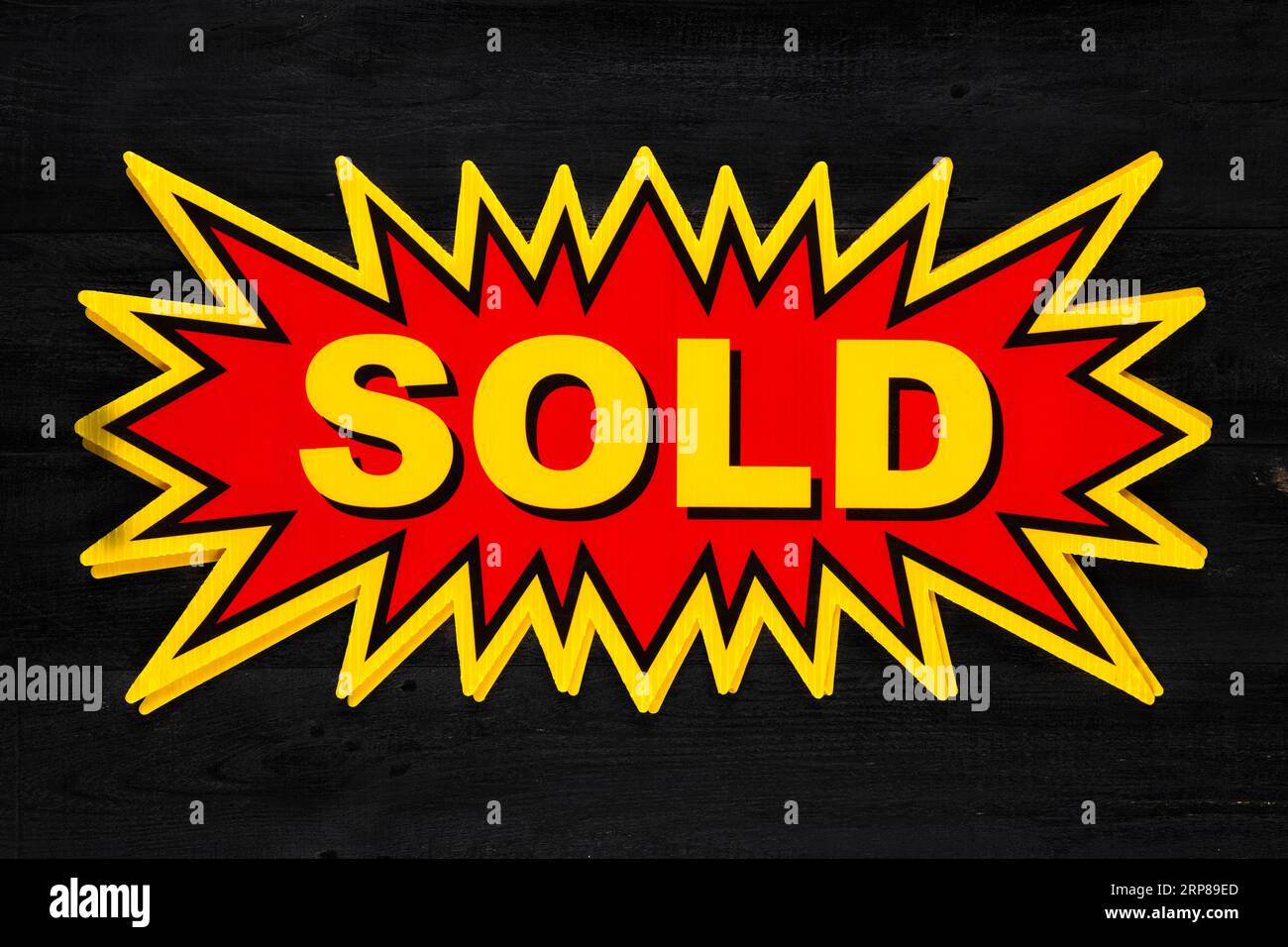 Red real estate sign with Sold in yellow on a black background. Real