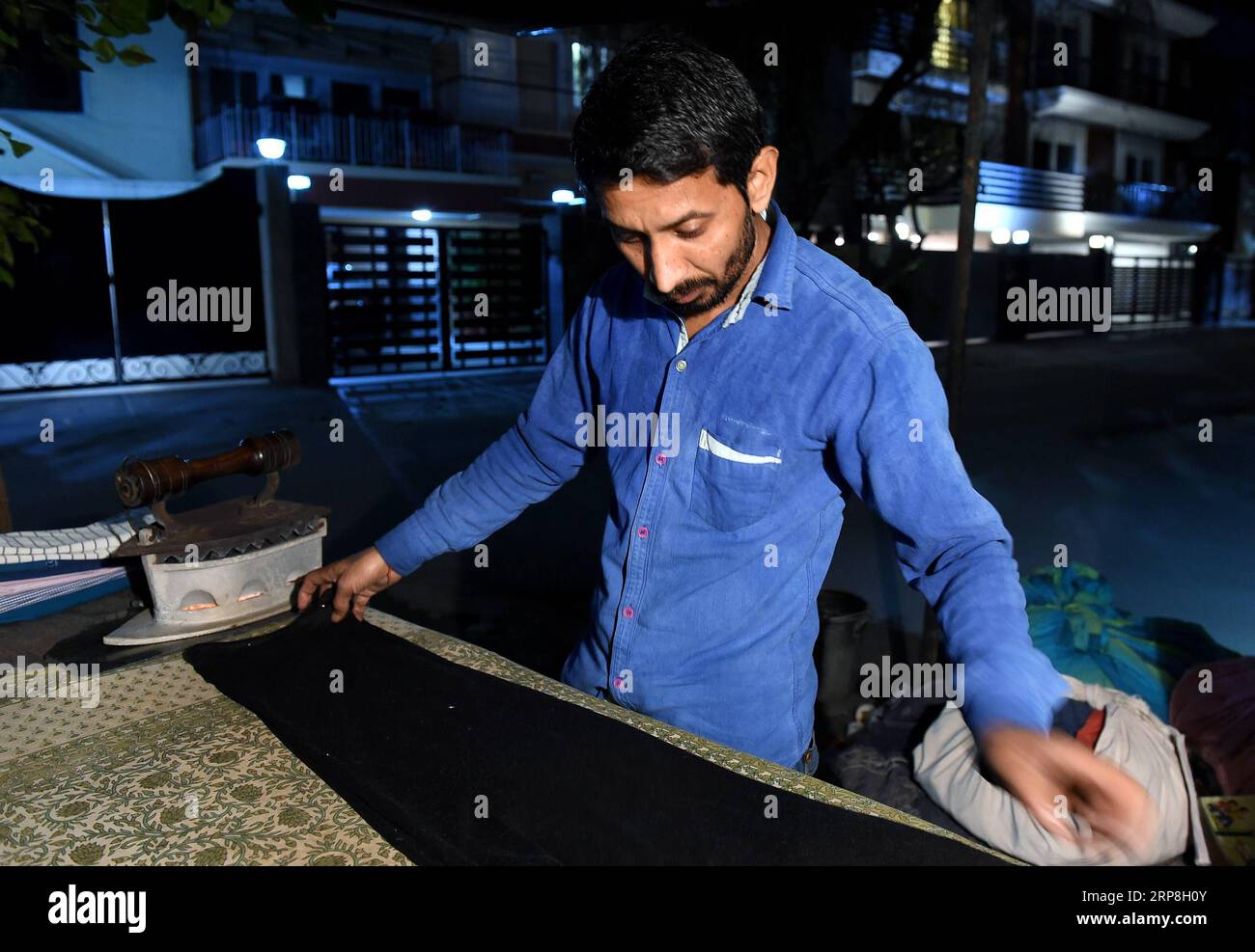 (190306) -- NEW DELHI, March 6, 2019 (Xinhua) -- The vendor irons clothes at his stand in New Delhi, India, March 5, 2019. The street vendor inherited a clothes-ironing stand from his father, which has been here for about 60 years. The vendor and his wife work about ten hours a day, earning 10 Indian Rupees (about 0.14 U.S. dollar) for ironing one piece of clothes with the total income of about 6,000 Indian Rupees one month. (Xinhua/Zhang Naijie) INDIA-NEW DELHI-CLOTHES-IRONING STAND PUBLICATIONxNOTxINxCHN Stock Photo