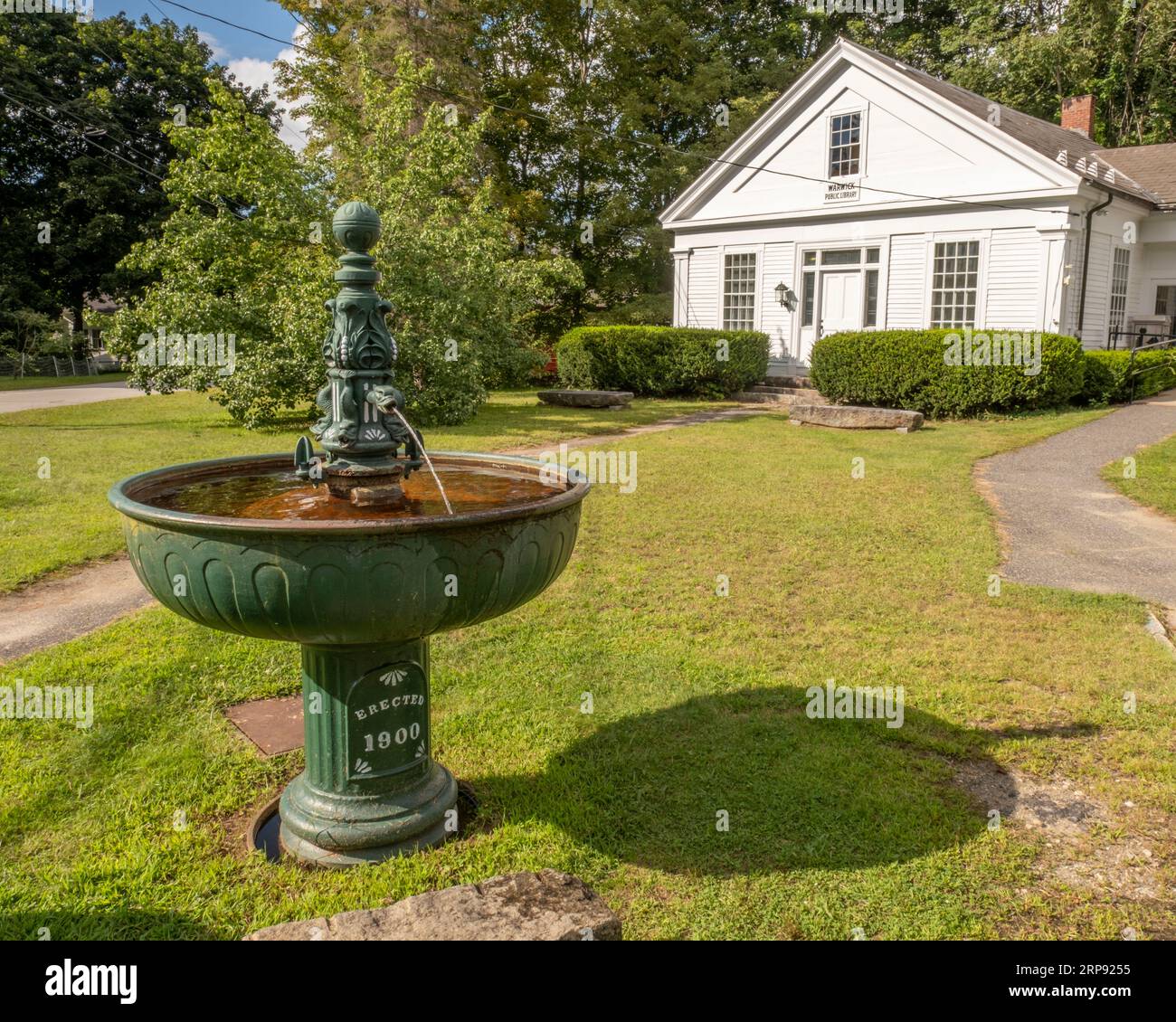 An old water fountain from 1800 sits in front of the Warwick Town Library Stock Photo