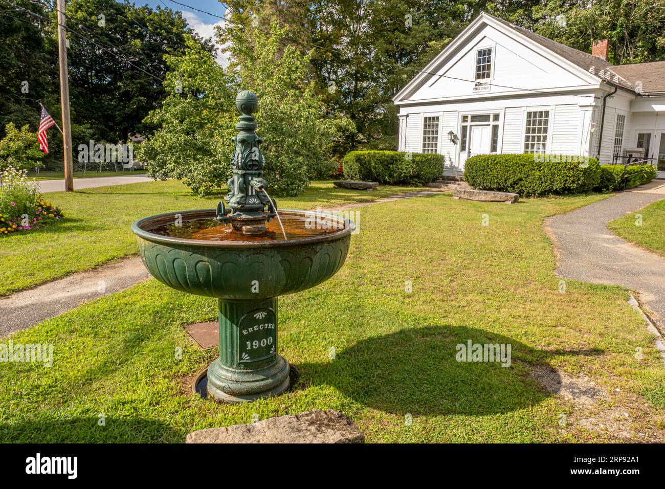 An old water fountain from 1800 sits in front of the Warwick Town Library Stock Photo
