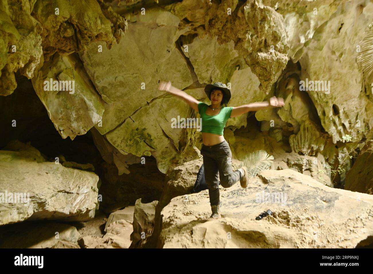 Pretty Asian woman jumping with happiness and cheerfulness at Tham Hup Pa Tat and is a popular tourist attraction for Thai tourists. Stock Photo