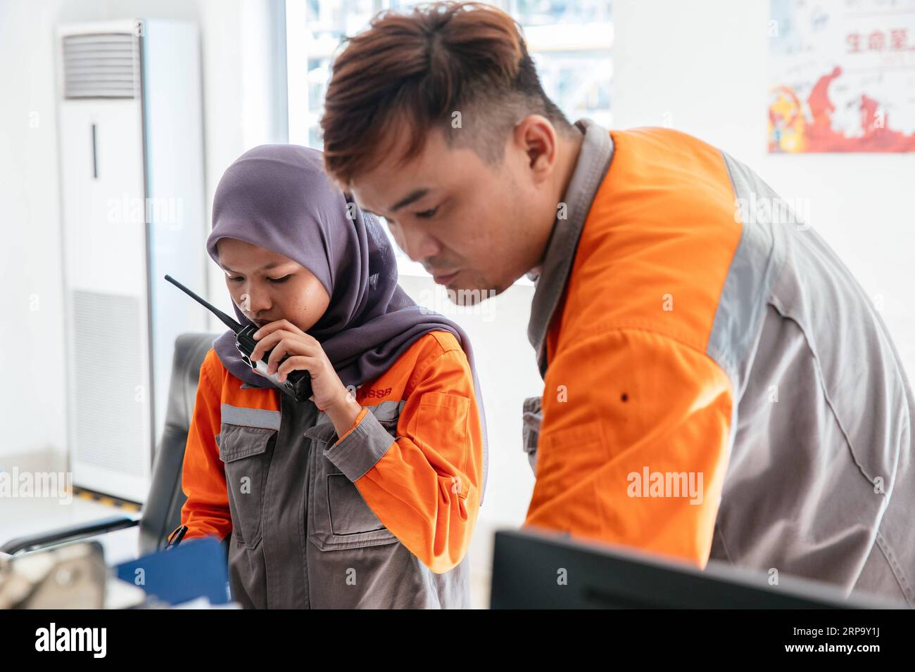 (190419) -- KUALA LUMPUR, April 19, 2019 (Xinhua) -- Nur Fatihah Binti Zakaria (L) works at the coal preparation central control room at the Alliance Steel coking plant in Kuantan, Malaysia, April 15, 2019. At the beginning Malaysian college graduate Nur Fatihah Binti Zakaria had no idea about what steel production was all about, nor did she have any knowledge about speaking Chinese. But after almost two years working at the Alliance Steel at the Malaysia, China Kuantan Industrial Park, she now can perform her job skillfully, even making fun of her colleagues from China that not all of them sp Stock Photo