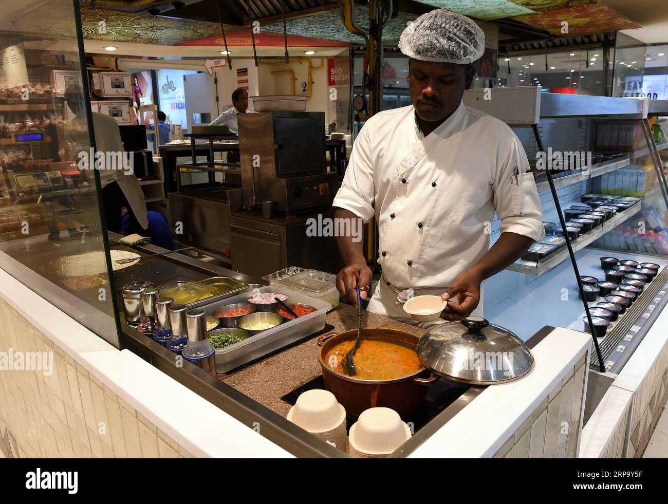 (190419) -- NEW DELHI, April 19, 2019 (Xinhua) -- An Indian chef serves curry soup for a customer at a supermarket in New Delhi, India, April 18, 2019. Dosa, a crispy paper-thin wrap with a spicy potato filling, eaten dipped in a tangy soup and a special sauce or chutney, is popular in southern India. (Xinhua/Zhang Naijie) INDIA-NEW DELHI-DOSA PUBLICATIONxNOTxINxCHN Stock Photo