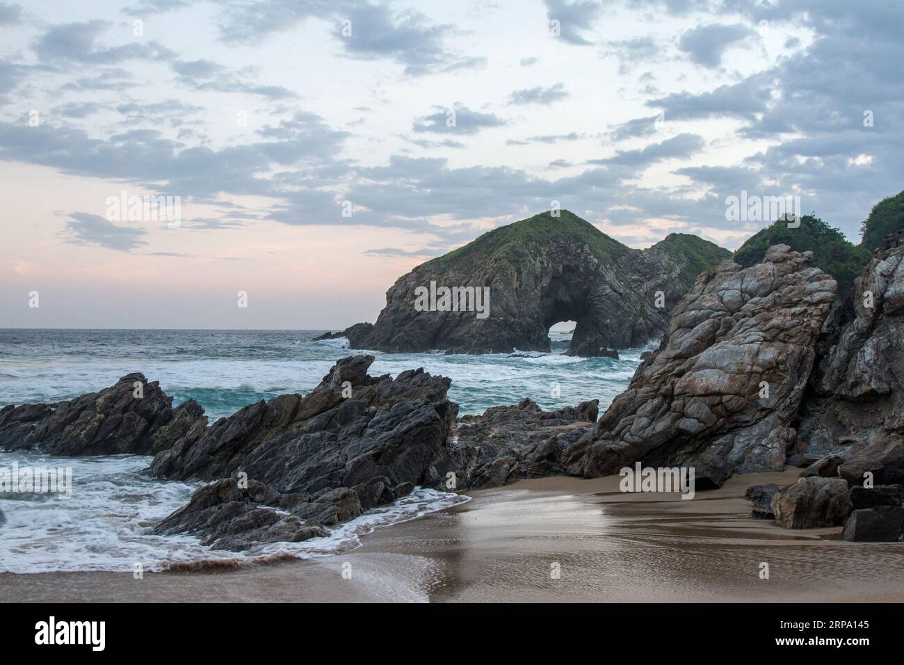 Sunset at the touristic Zipolite beach in Oaxaca,  Mexico.  Rocky beach with no people. Stock Photo