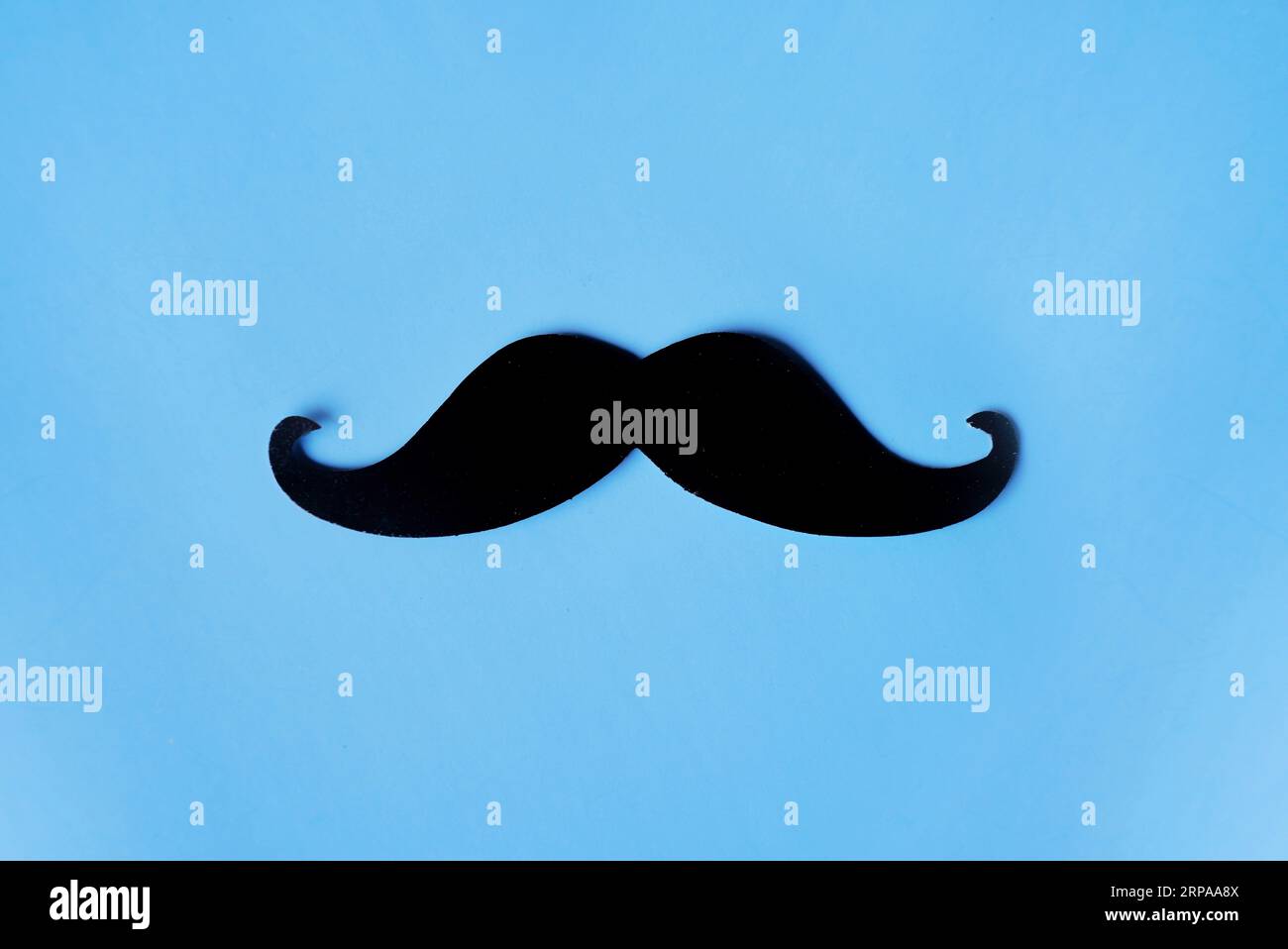 Top view image of fake mustache on blue background with copy space. Masculine, movember and hipster concept Stock Photo