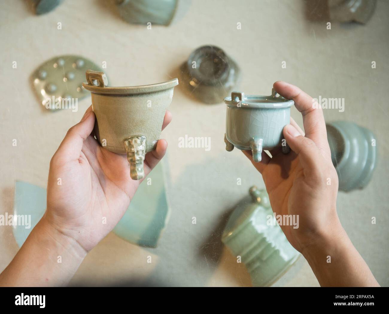 (190520) -- LONGQUAN, May 20, 2019 (Xinhua) -- Lin Song shows a piece in his collection of classical Longquan celadon incense burners (on the left) and the corresponding replica made by him in Longquan, east China s Zhejiang Province, May 20, 2019. Born in 1993, Lin Song is a native of Longquan, home to China s best celadon wares. He received professional training in both his hometown and Jingdezhen, another important porcelain hub of China. Lin had also followed other celadon artisans for years before setting up a studio back home in 2014, focusing on the replication of classical celadon ince Stock Photo