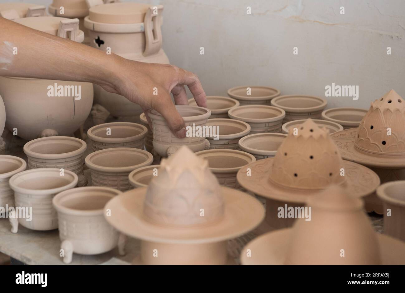(190520) -- LONGQUAN, May 20, 2019 (Xinhua) -- Lin Song checks clay bases for celadon incense burners at his studio in Longquan, east China s Zhejiang Province, May 20, 2019. Born in 1993, Lin Song is a native of Longquan, home to China s best celadon wares. He received professional training in both his hometown and Jingdezhen, another important porcelain hub of China. Lin had also followed other celadon artisans for years before setting up a studio back home in 2014, focusing on the replication of classical celadon incense burners. Lin s personal collection has grown to over 40 celadon incens Stock Photo