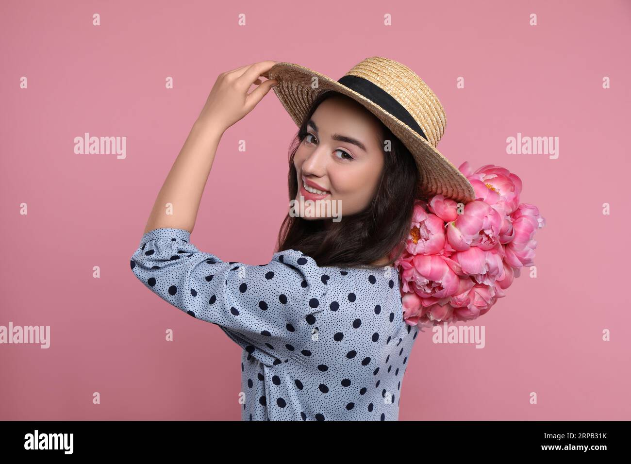 Beautiful young woman in straw hat with bouquet of peonies on pink ...