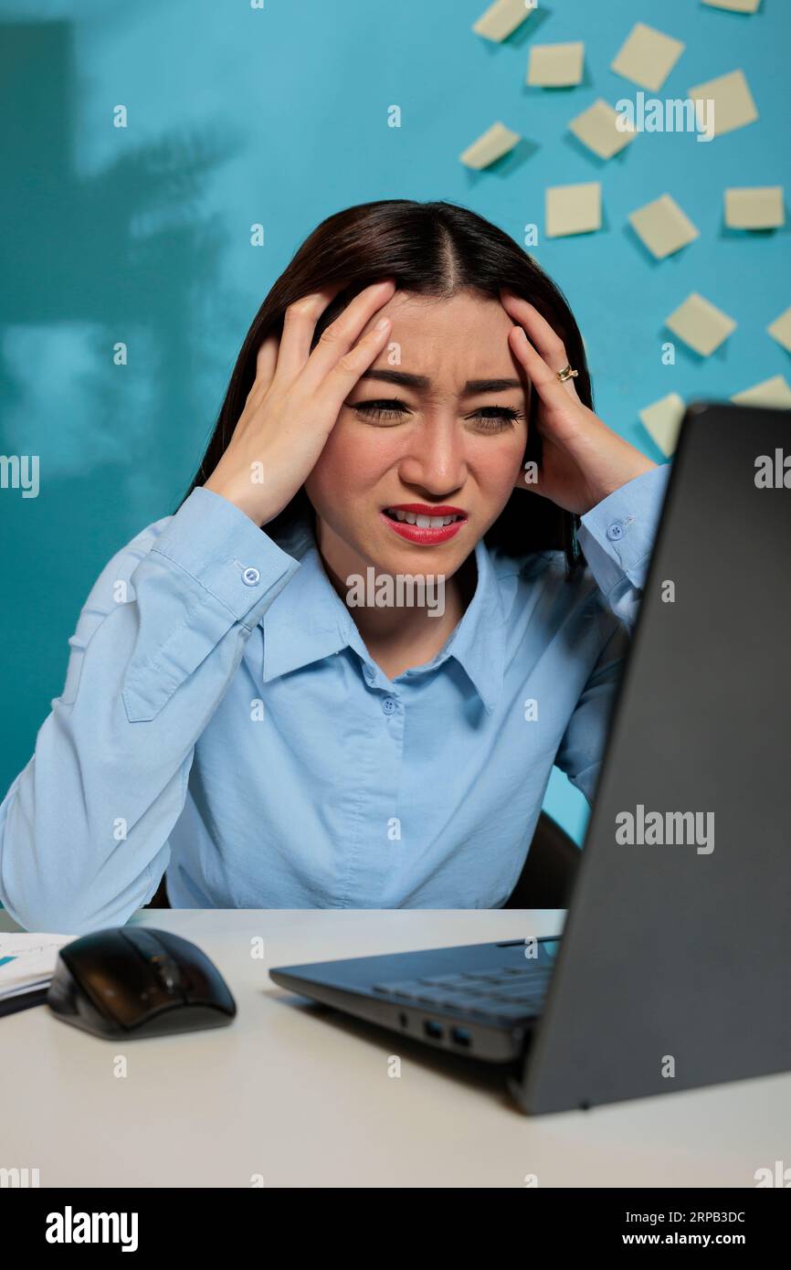 Female employee with headache rubbing temples looking frustrated at