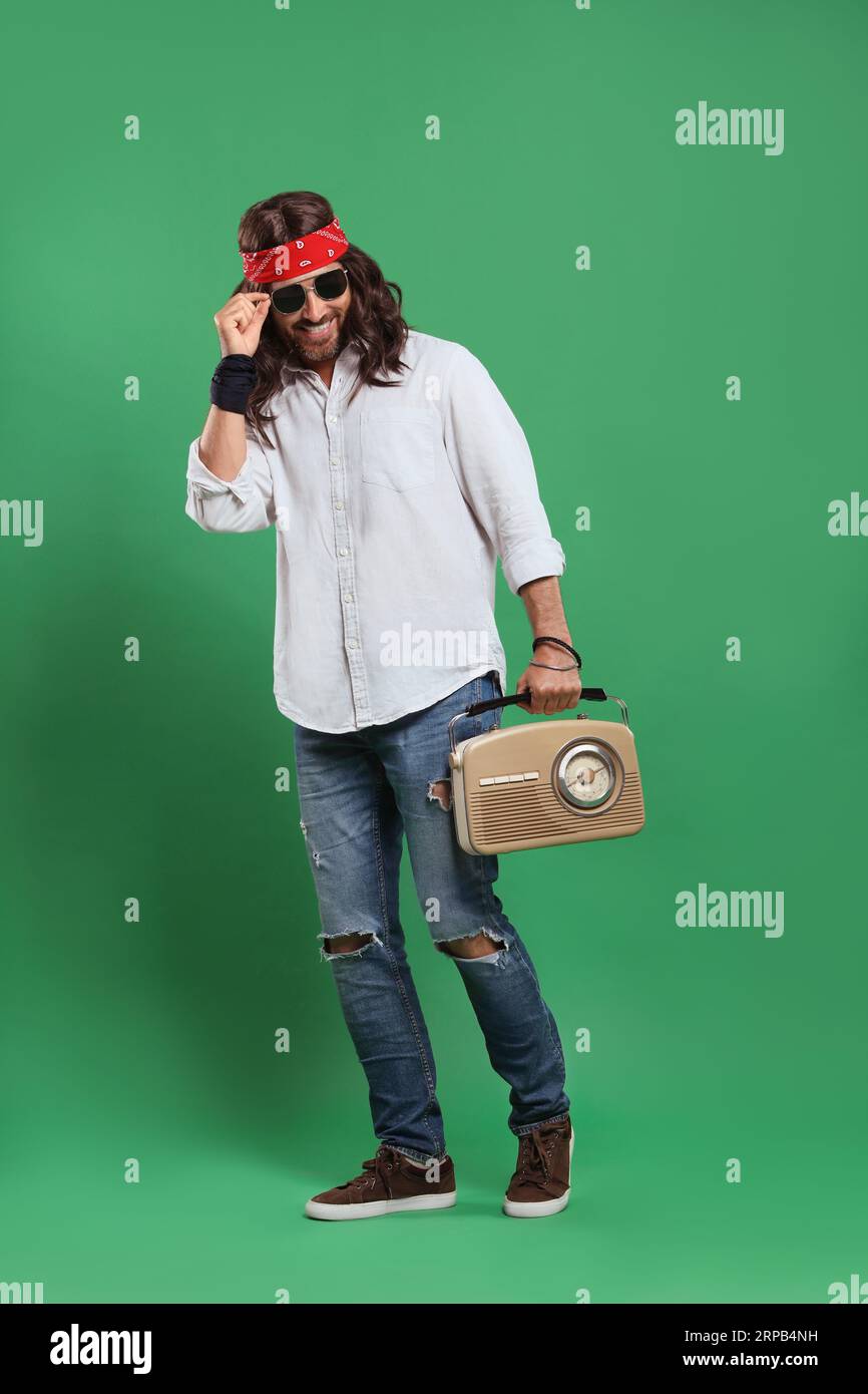 Stylish hippie man in sunglasses with retro radio receiver on green background Stock Photo