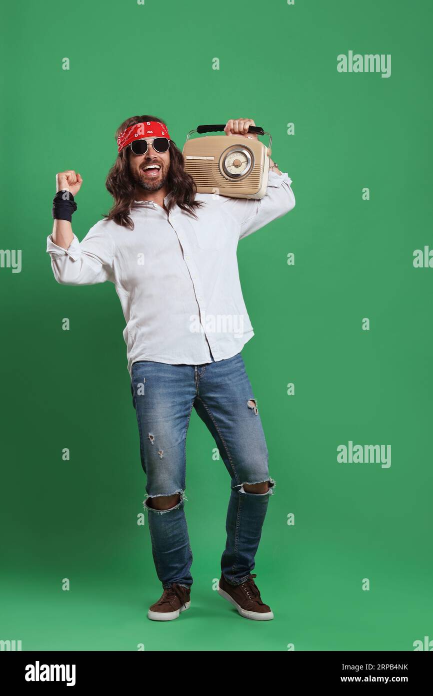 Stylish hippie man in sunglasses with retro radio receiver on green background Stock Photo