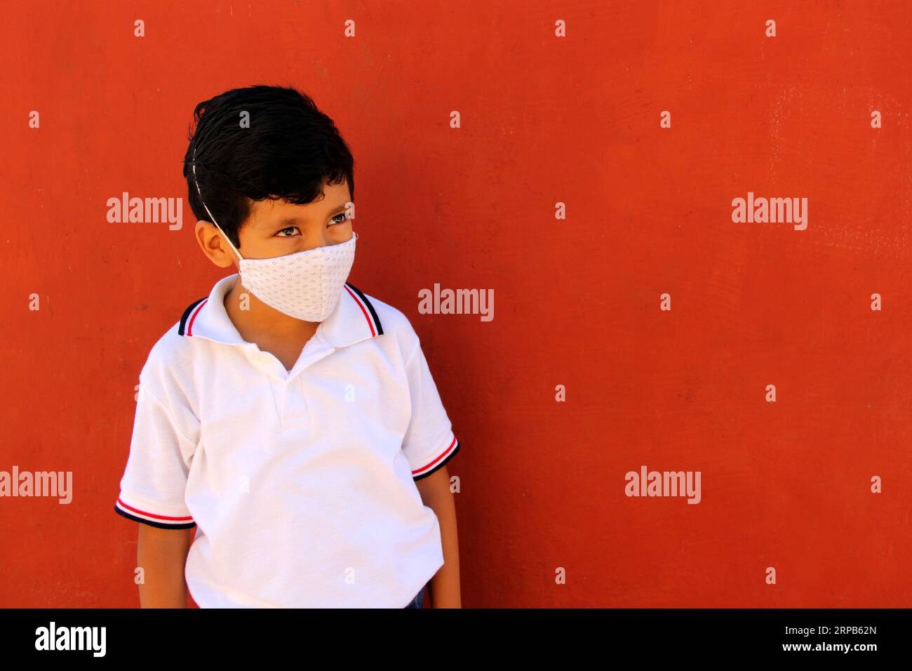 Happy and pensive Latino 8 year old boy wearing white school uniform