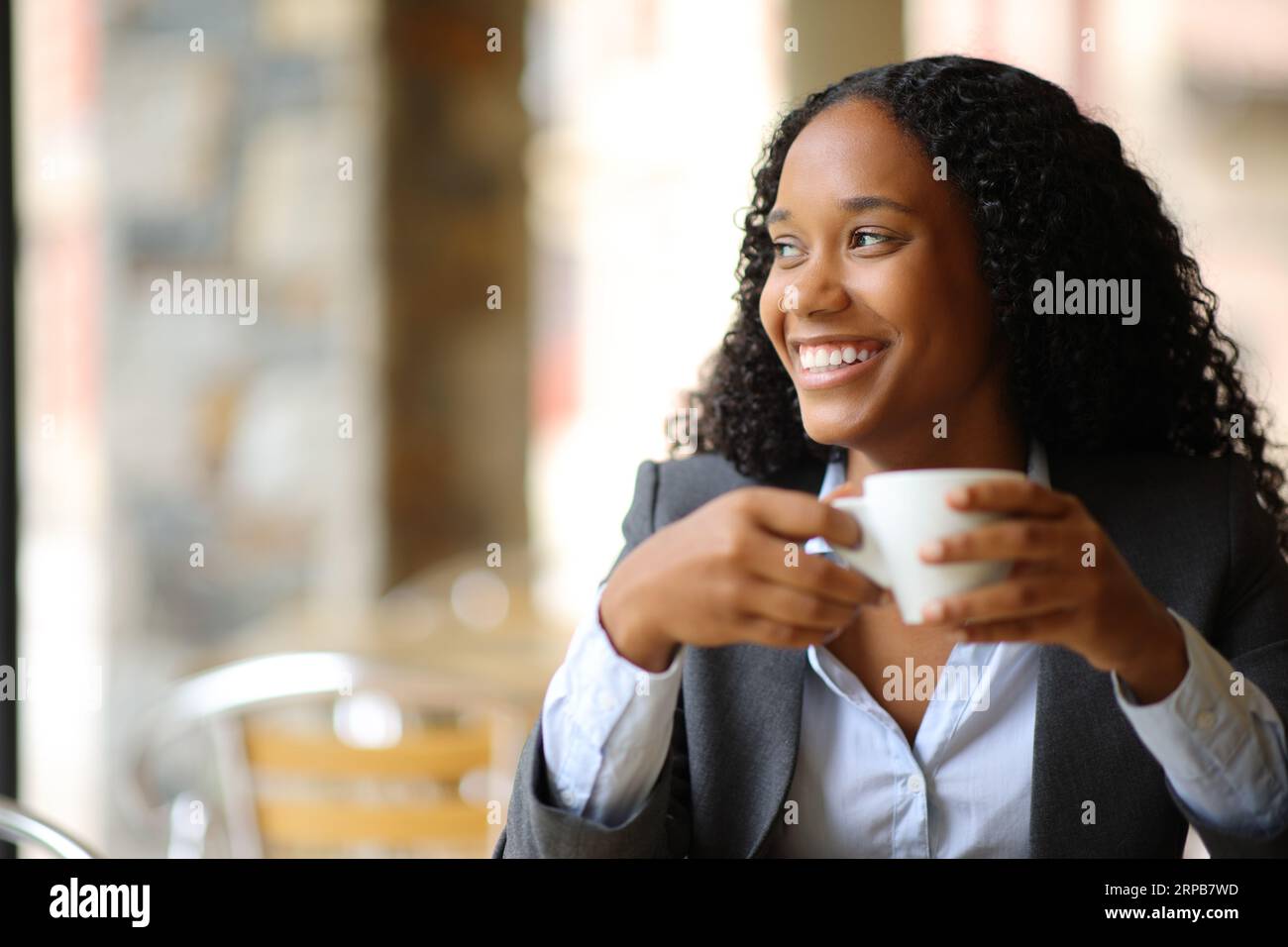 Happy black executive looking at side in a coffee shop terrace Stock Photo