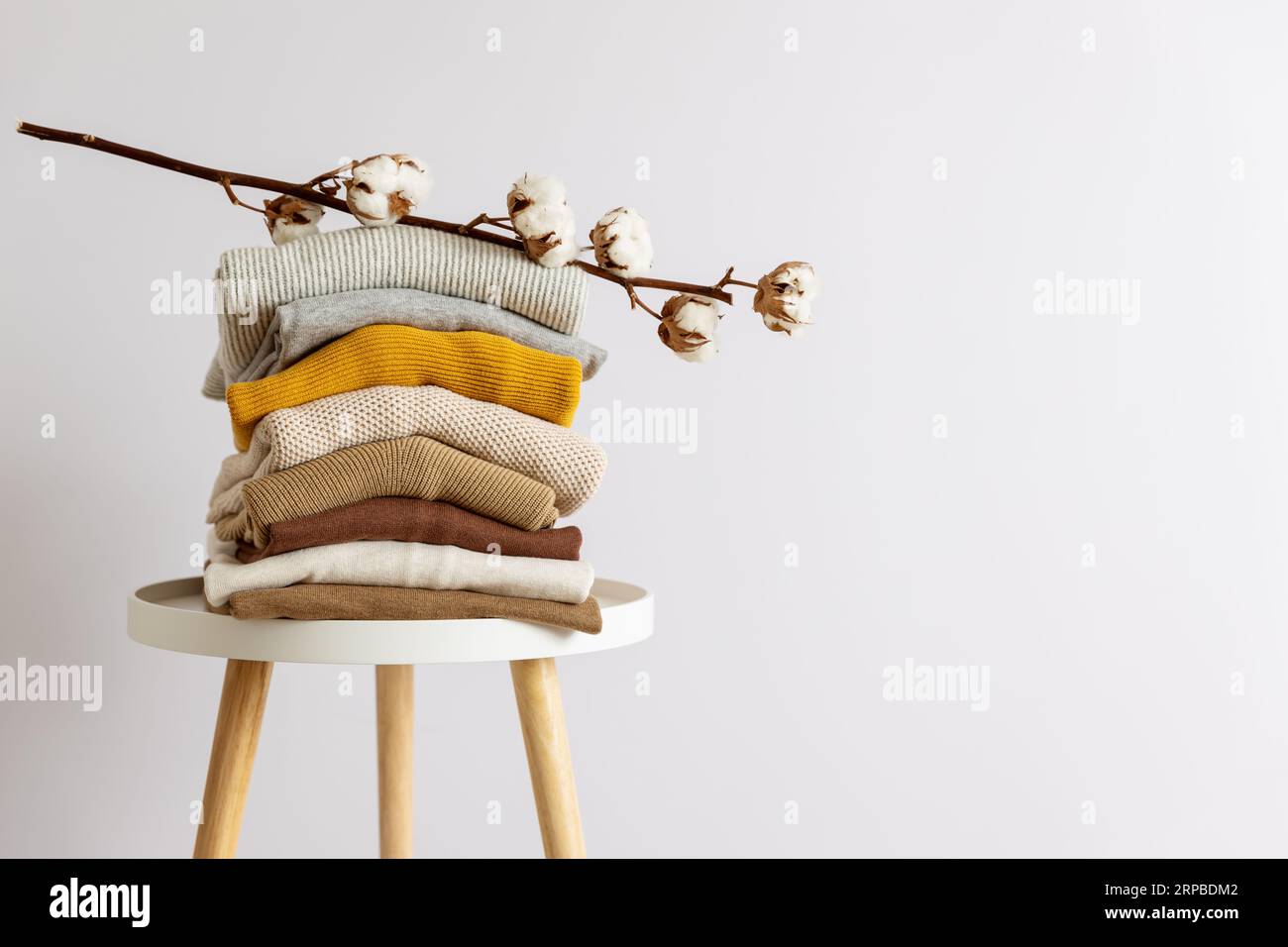 Stack of folded casual garments placed on table against white background. Stock Photo