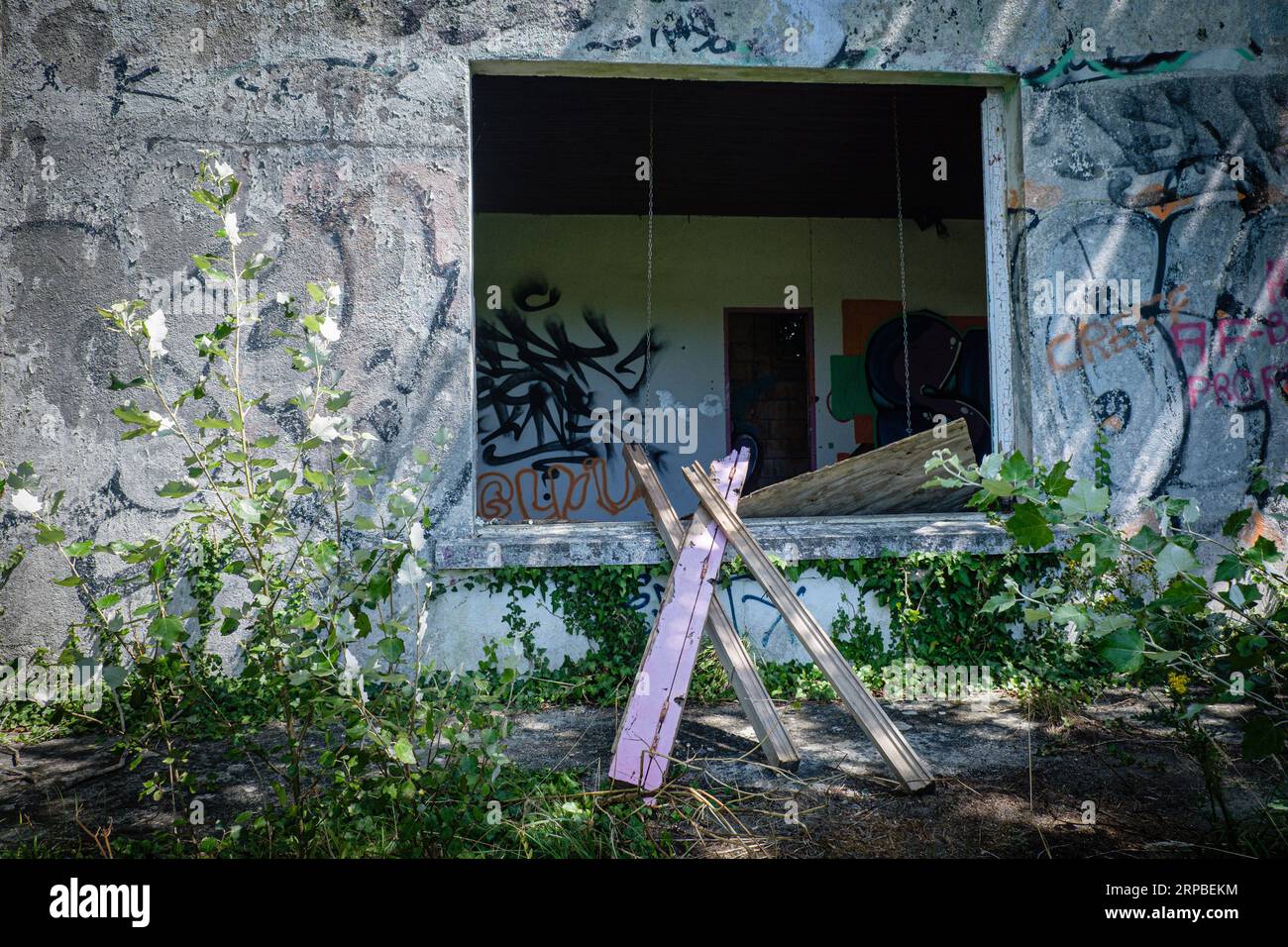 Wooden boards in front of the window of an abandoned house with graffiti. Stock Photo