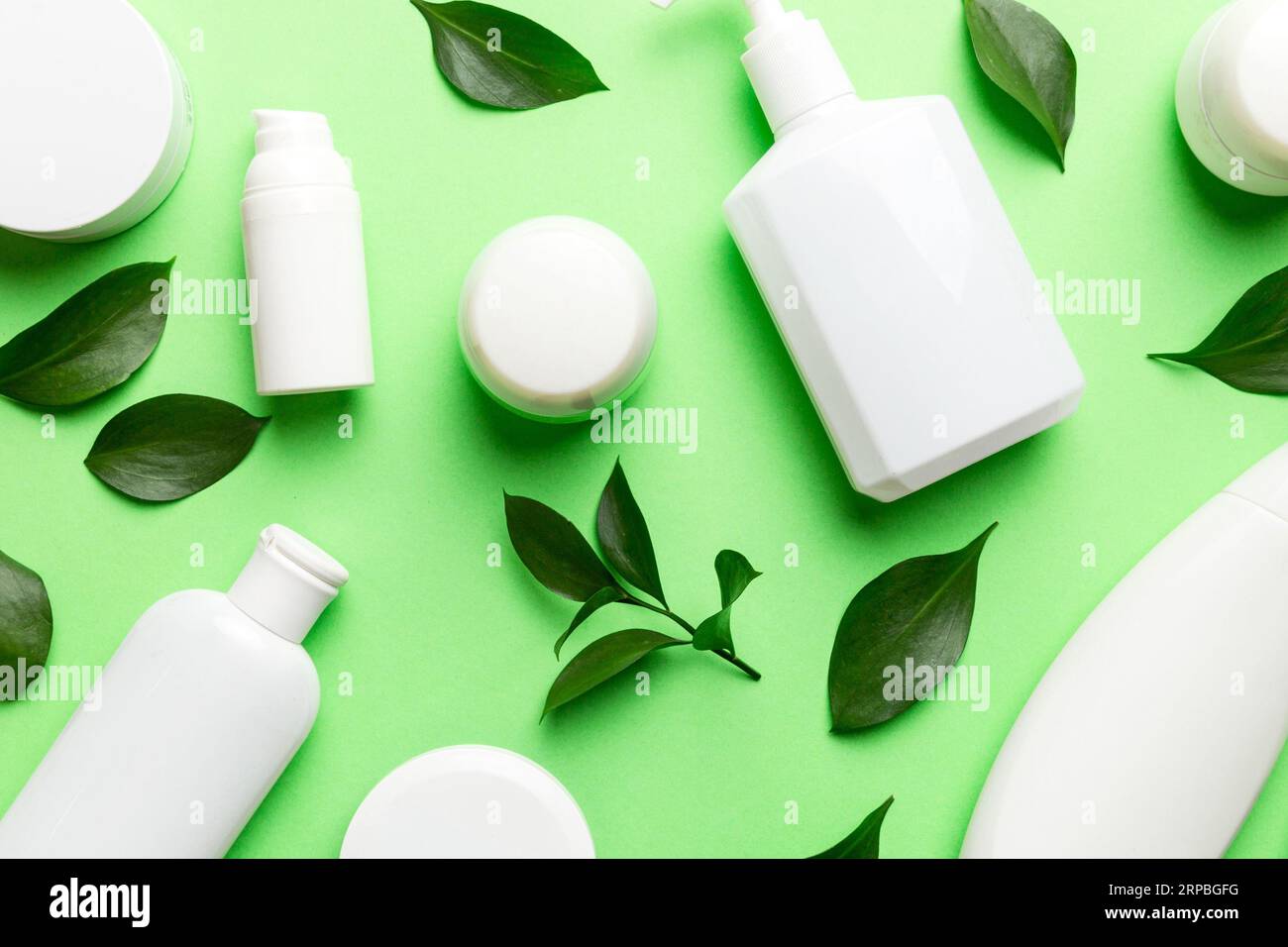 Organic cosmetic products with green leaves on color background. Flat ...