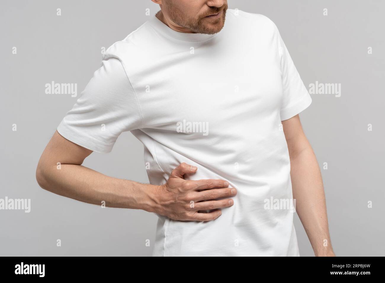 Closeup hand man touches unwell body side suffers from unbearable pain isolated studio background. Stock Photo