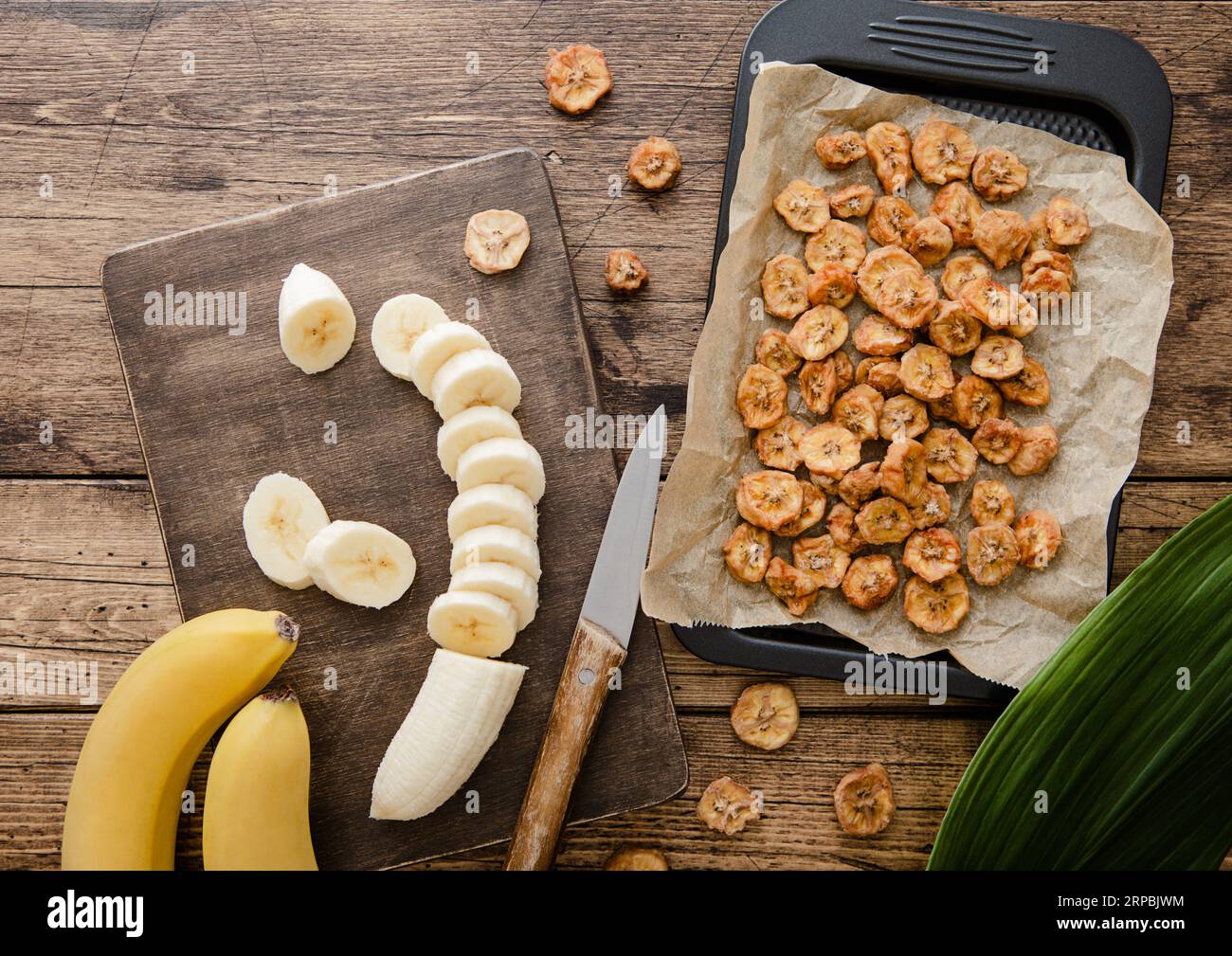 View of Raw banana slices with dried banana chips on wooden background with ...