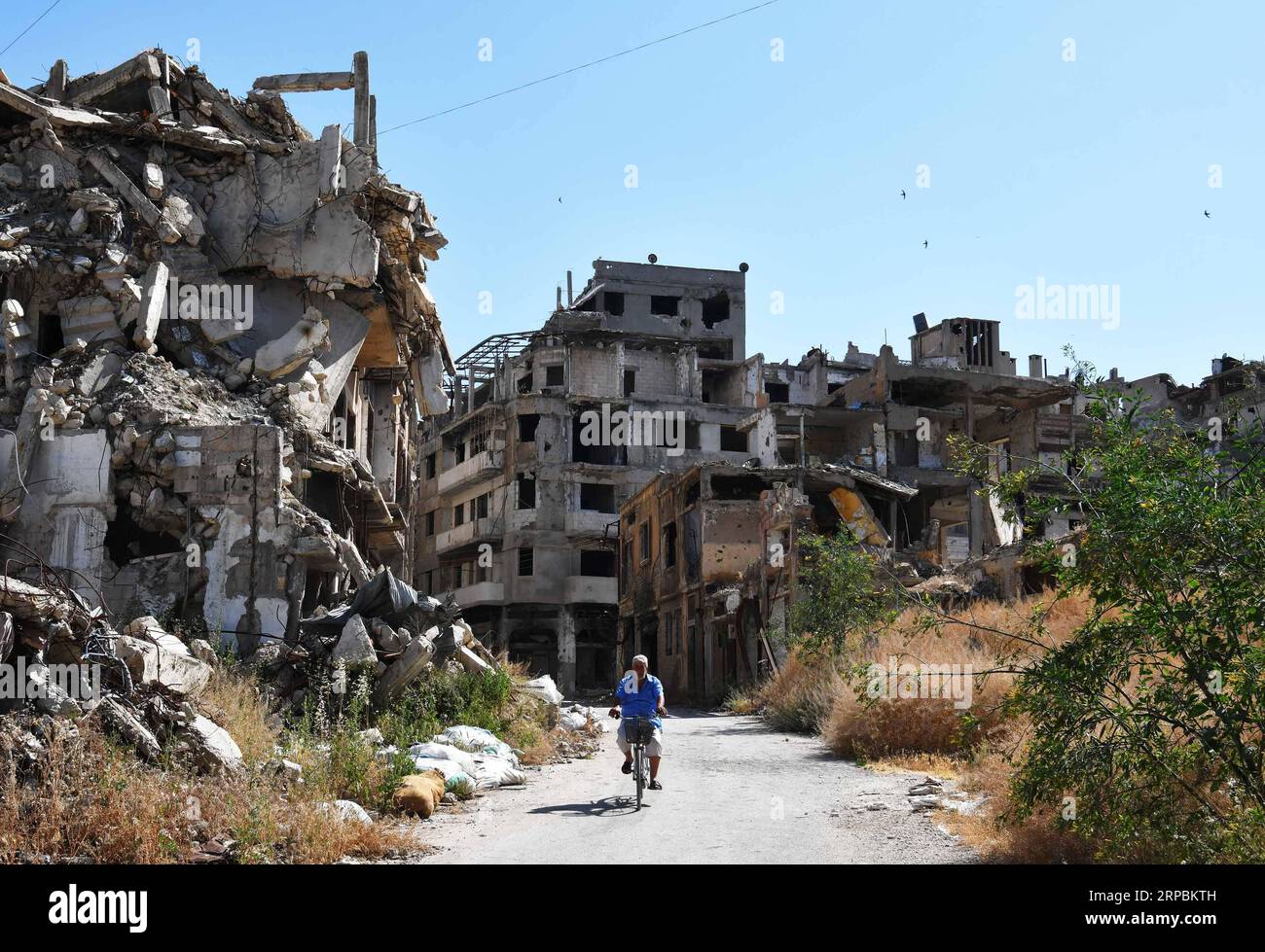 (190611) -- HOMS, June 11, 2019 -- Kamal Shtaiwi rides his bicycle back home in the Wadi al-Sayeh street in the central city of Homs, Syria, May 29, 2019. Kamal Shtaiwi, 58, enjoys returning to his home with his wife and four children, even though it is surrounded by the destruction of war. TO GO WITH Feature: Displaced Syrian family back home, sweet home amid rubble ) SYRIA-HOMS-DISPLACED SYRIAN FAMILY-HOME AmmarxSafarjalani PUBLICATIONxNOTxINxCHN Stock Photo