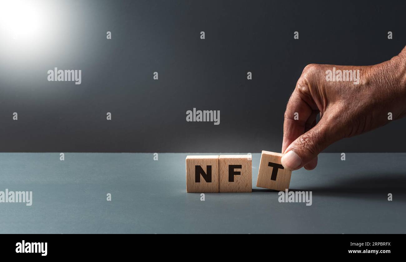hand posing wooden cubes with the letters N F T , concept of non fungal