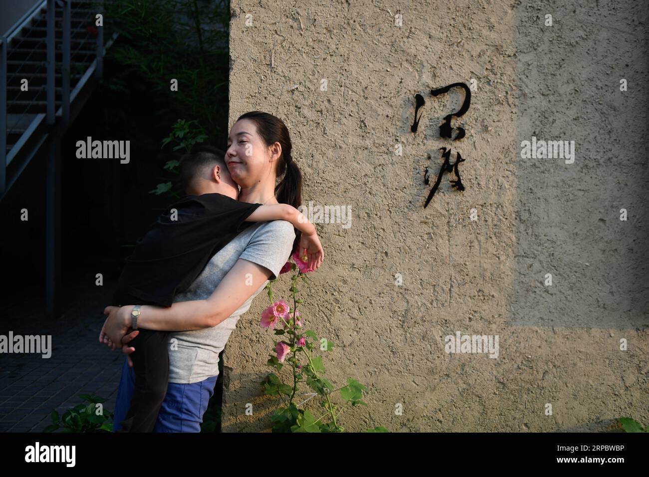 (190616) -- TONGLU, June 16, 2019 (Xinhua) -- A homestay owner holds her son at the courtyard in Qinglongwu of Tonglu County, east China s Zhejiang Province, June 15, 2019. In recent years, Tonglu County has been rolling out measures to develope rural tourism industry. Qinglongwu was transformed into a base of rural guesthouses for tourists to experience the countryside life. (Xinhua/Huang Zongzhi) CHINA-ZHEJIANG-TONGLU-RURAL TOURISM (CN) PUBLICATIONxNOTxINxCHN Stock Photo