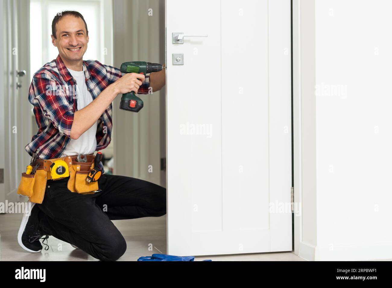 Master with screwdriver installs door hinges. Stock Photo