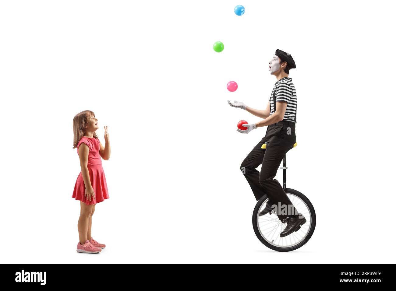 Full length profile shot of a girl looking at a mime juggling and ...