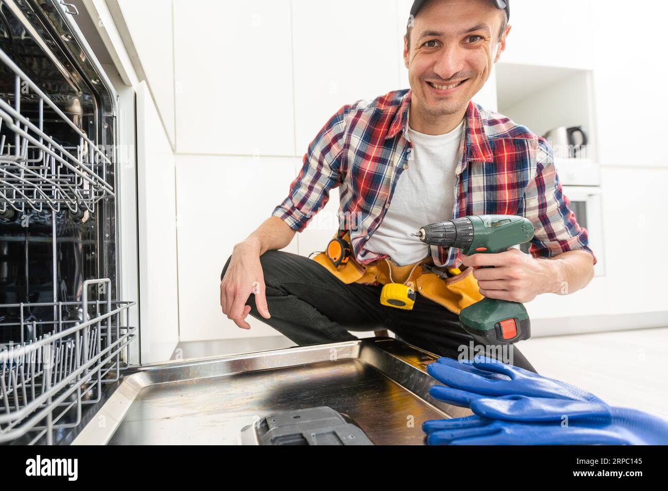Process of dishwashing machine installation. Young African service man setting up dishwasher in