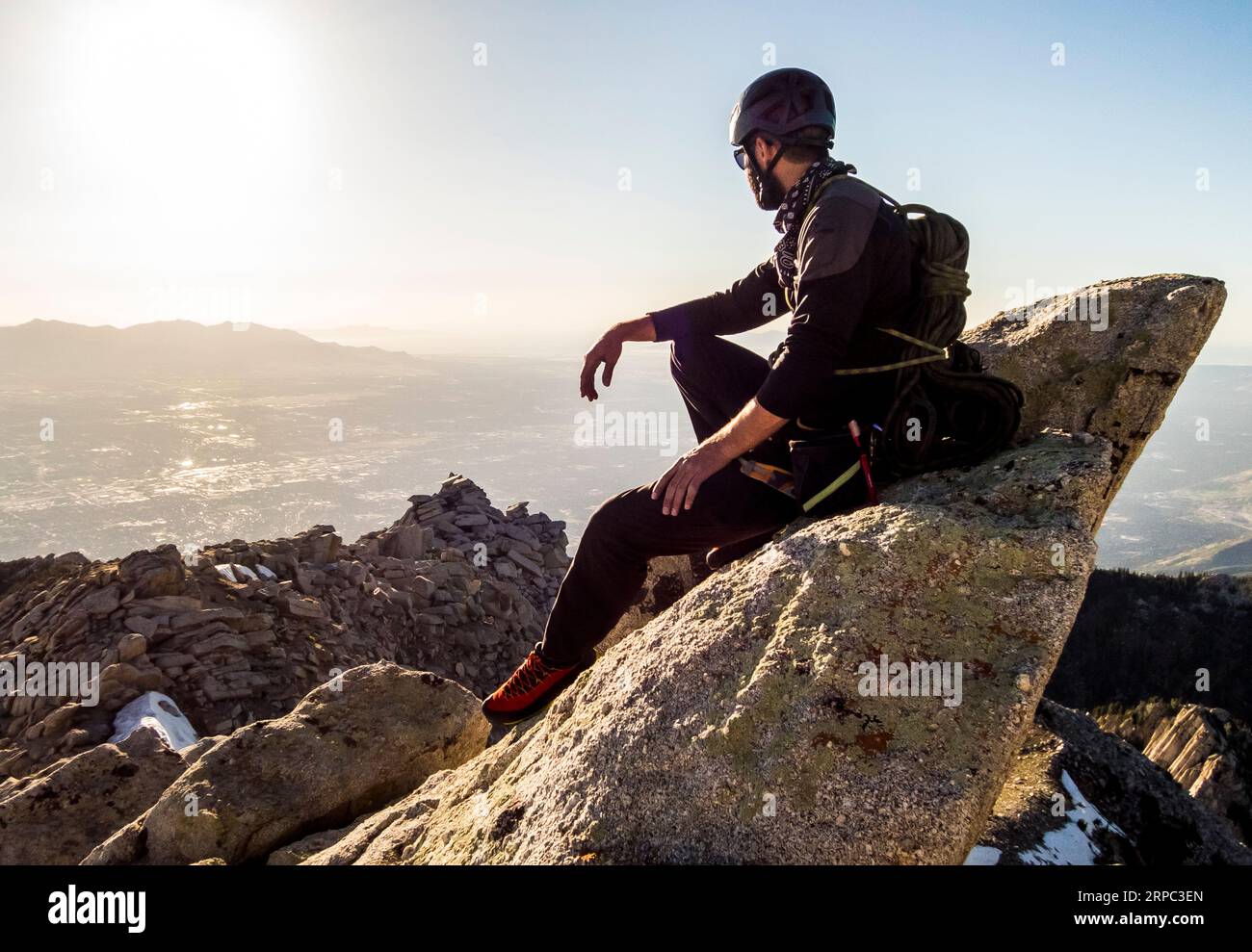 A Man Enjoys The View Of The Salt Lake Valley While Taking A Break As He Hikes Down From Summit Of Lone Peak After Rock Climbing To The Top Stock Photo