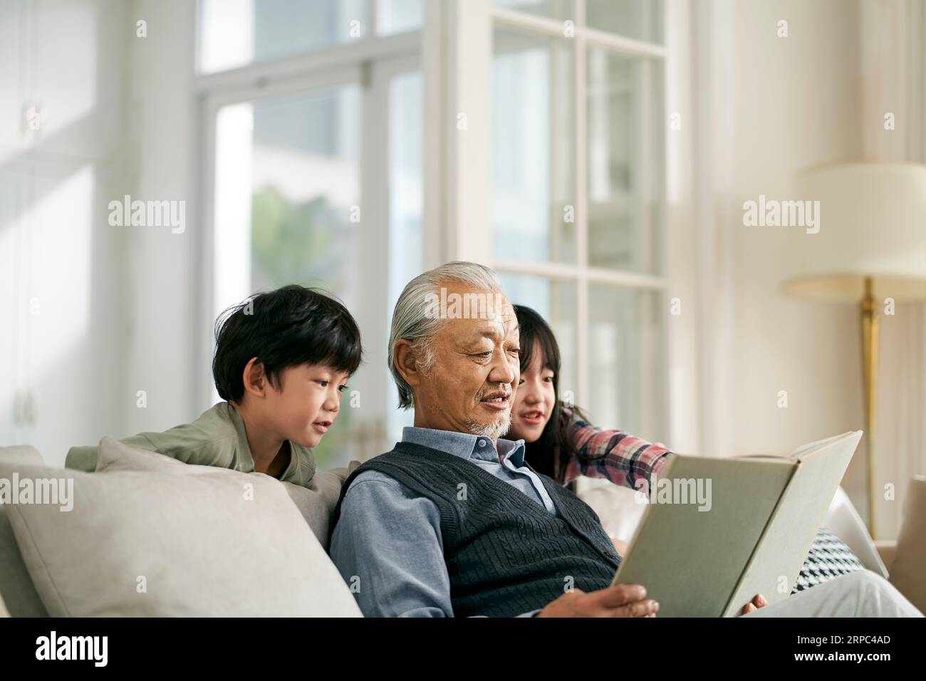 asian grandfather having a good time telling story to cute grandson and granddaughter Stock Photo