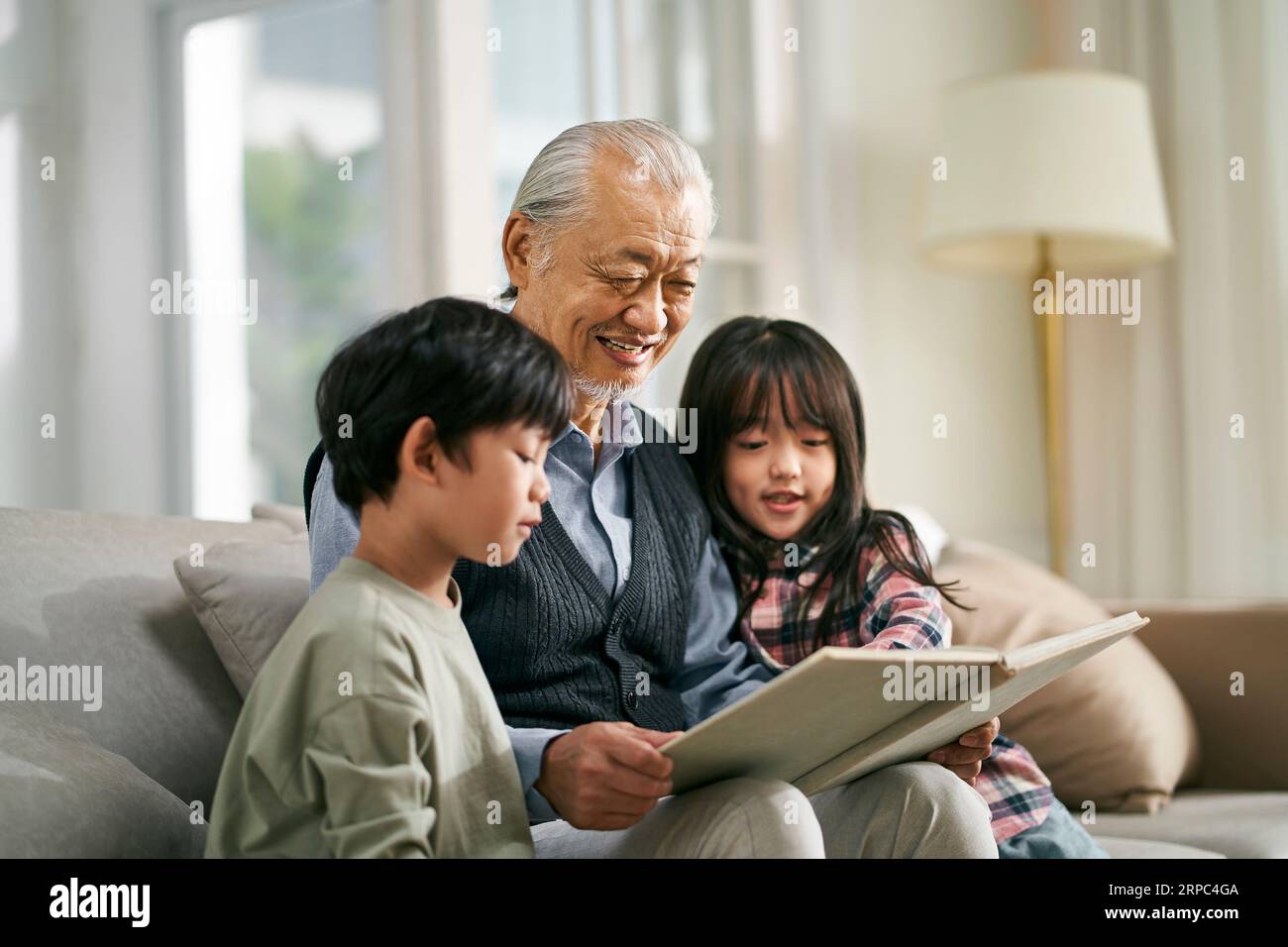 asian grandfather having a good time telling story to cute grandson and granddaughter Stock Photo