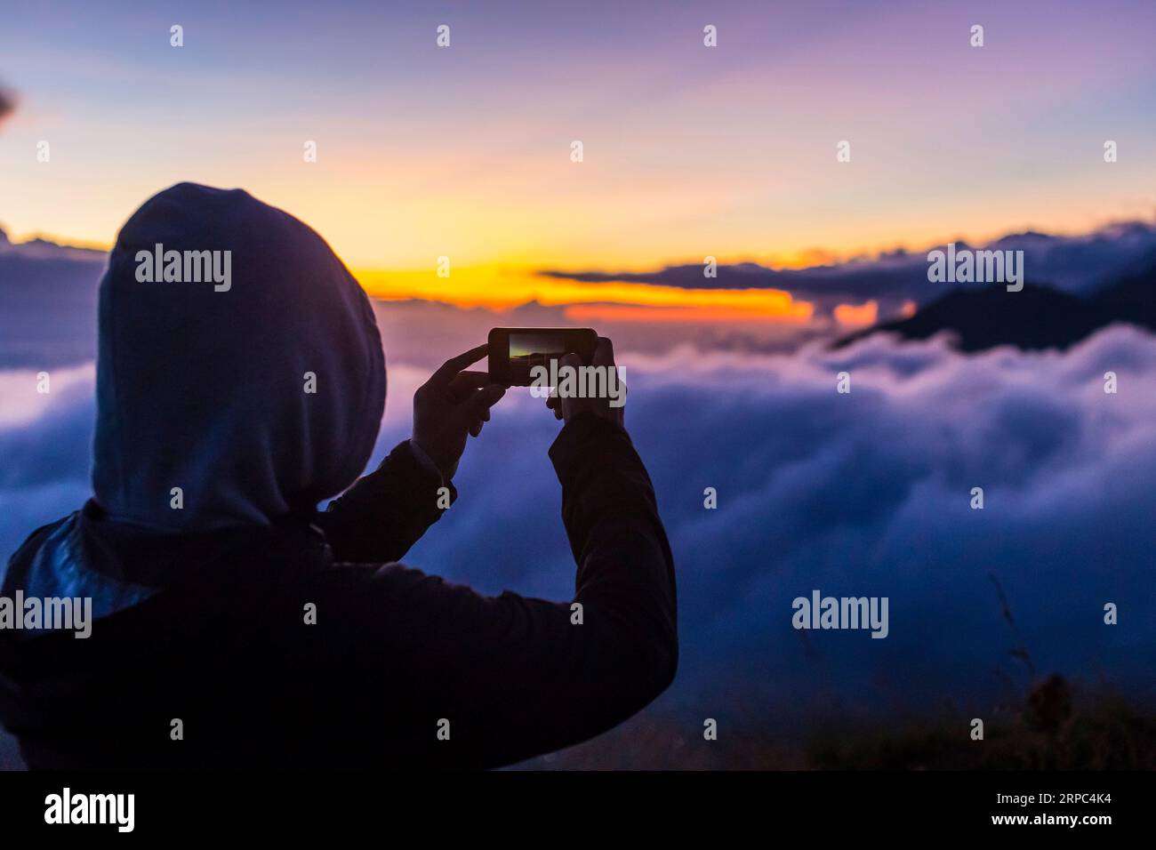 Man takes photos with smartphone in mountains at sunrise Stock Photo