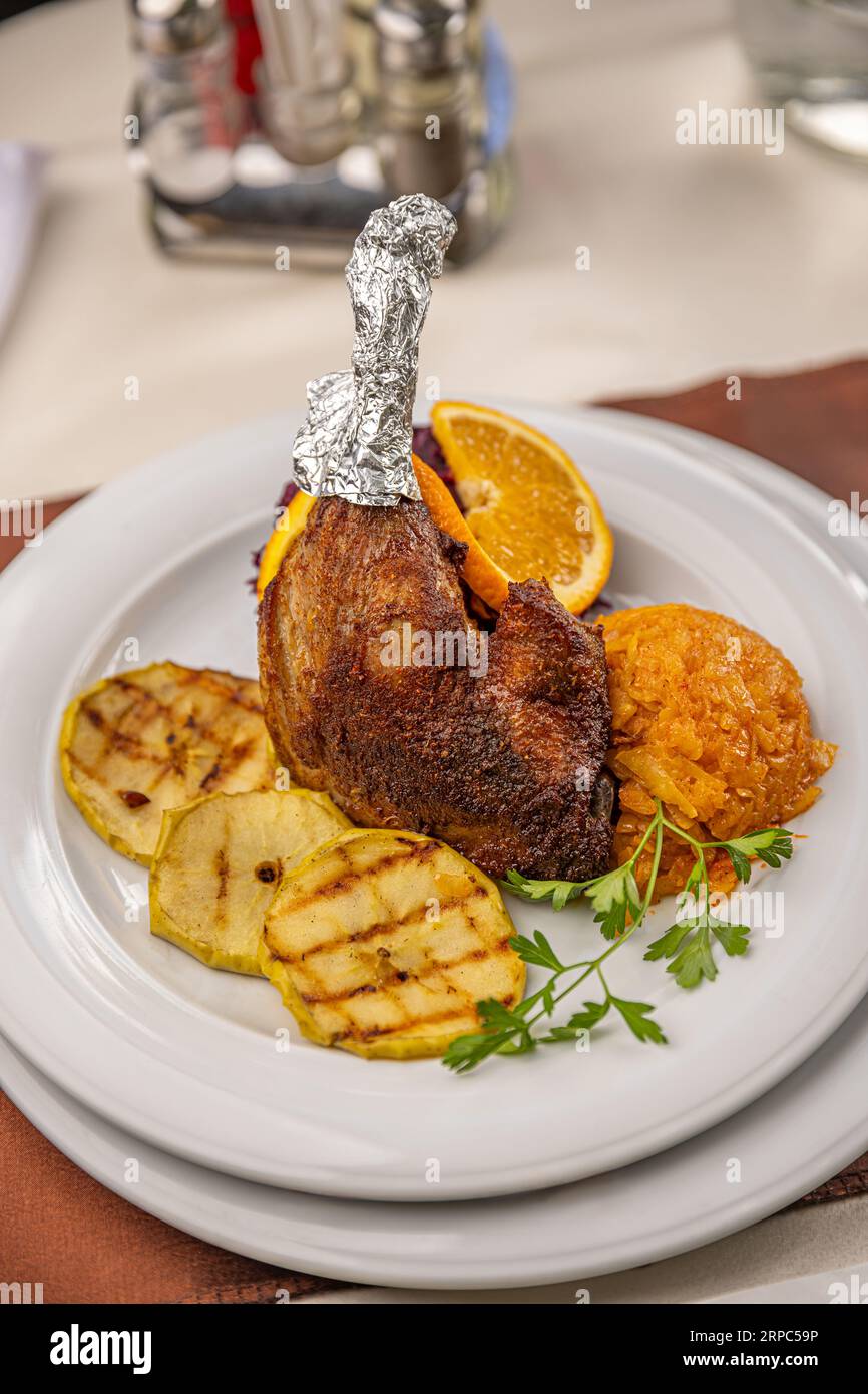 Plate of roast duck legs served with roasted pear and cabbage Stock