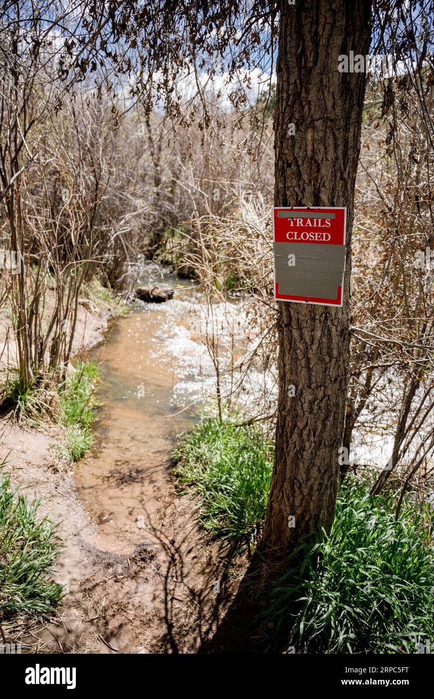 Sign reading 'trails closed' with stream of water in background Stock Photo