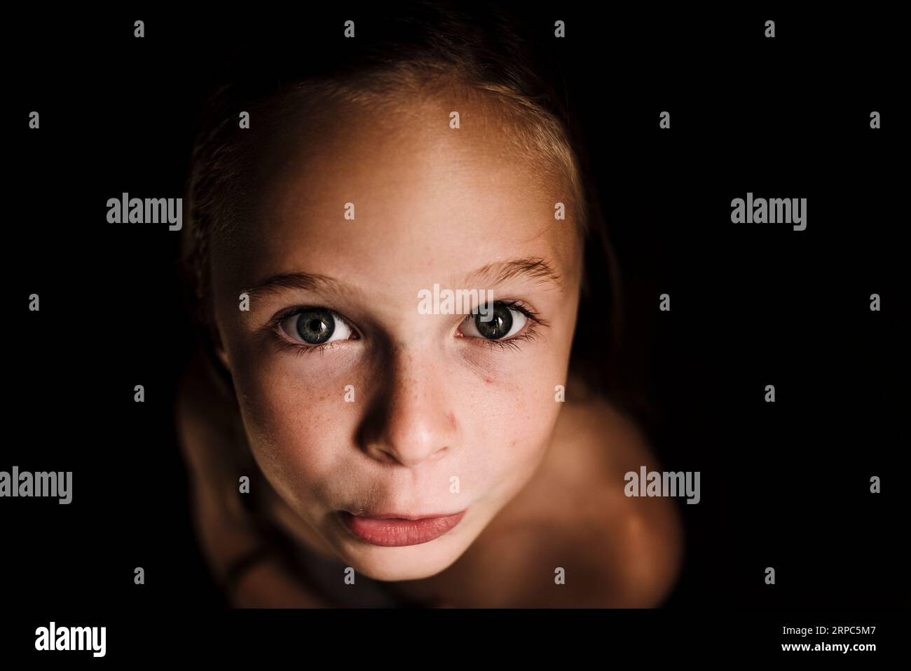 Portrait of little girl with wet hair in low light and dark background Stock Photo